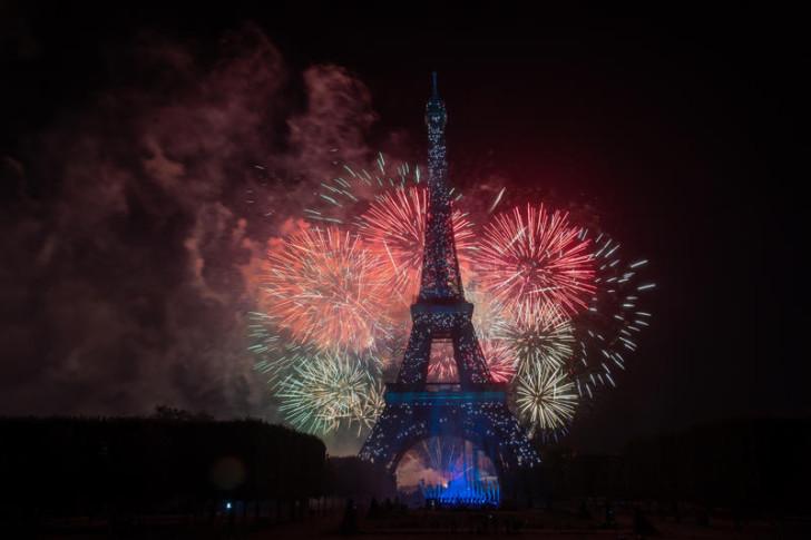 La Tour Eiffel, de nuit, entourée par un feu d'artifices 